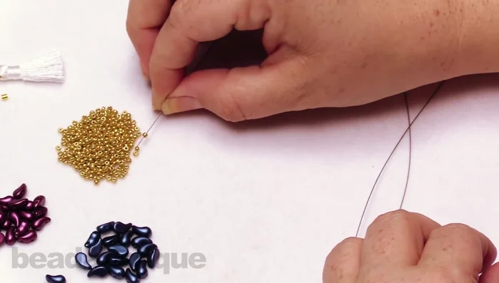 On one wire, string three gold seed beads. On the other wire, string two gold seed beads.