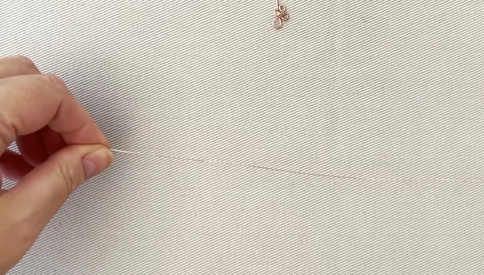 Take a 30-40cm length of 0.4mm wire and thread it through the smaller loop. Wrap the wire around the connecting point of the two loops four times, then twice around the smaller loop only, securing it.