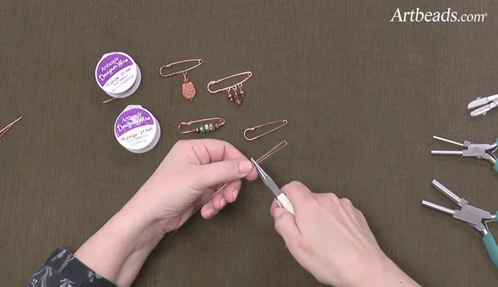 Form the base loop: Measure about an inch and a quarter, hold both wires tightly, and bend the short end up. Wrap the short end tightly around the longer end and snip off the excess.