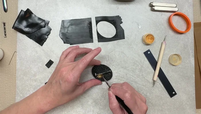 Apply gold M powder to the back of the brooch, blending edges for a seamless finish.