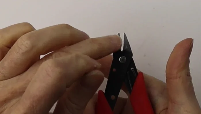 Center the loop with a flick of the wrist and flatten it using flat pliers to avoid sharp ends.