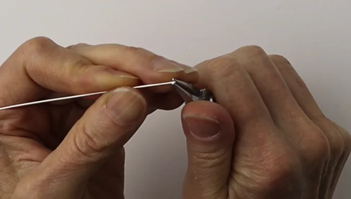 Center the loop with a flick of the wrist and flatten it using flat pliers to avoid sharp ends.