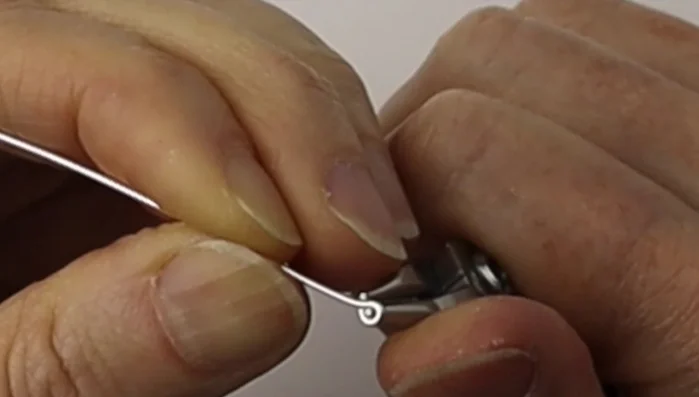 Center the loop with a flick of the wrist and flatten it using flat pliers to avoid sharp ends.