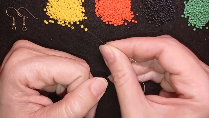 Prepare thread and pick up 8 yellow beads. Make a knot by looping the thread twice and pulling tight.