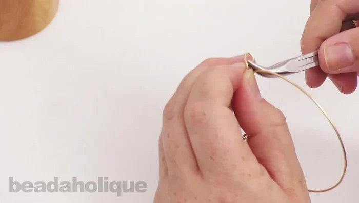 Open the loops at both ends of the bangle. Attach jump rings to the bangle and attach the charms.