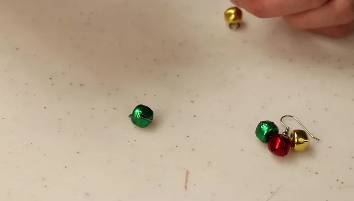 Repeat steps 3 and 4 until all jingle bells are attached to create the desired earring length and design. Pay attention to the consistent placement of the bells (described in the video around timestamp 290.86).