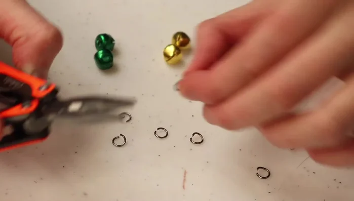 Open the O-rings using needle-nose pliers. Gently bend the wire open enough to slide a jingle bell onto it.