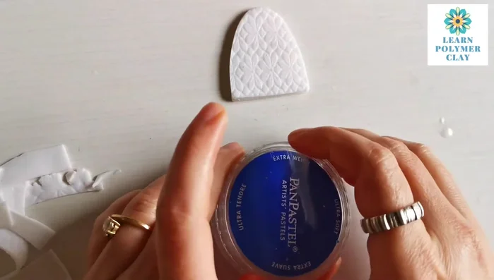 Use pan pastels (blue and purple) to color the clay, blending with fingers or a brush. Add unicorn purple metallic powder for sparkle.