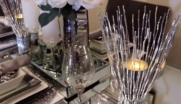 Arrange the mirror pillow candle holders, silver picture frame, and silver vases around the mirror tray.