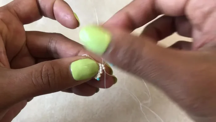 Add design: Begin adding colored beads to create a design (e.g., a triangle).