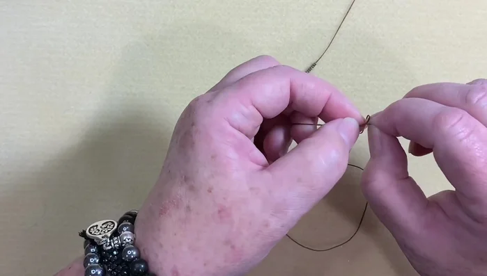 Tie a small knot at the end of the linen to secure the beads.
