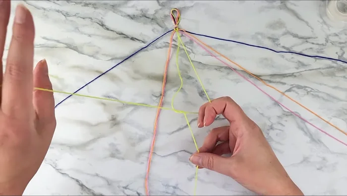 Tie two backward knots with the two middle strands to form the first chevron 'V'.