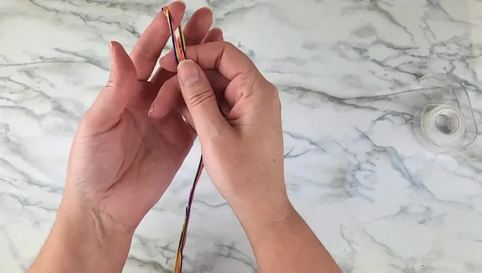 Gather all strands, fold in half, make a loop, and tie a knot. This loop will be used to fasten the bracelet.