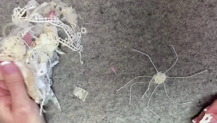 Add lace: Start weaving scrap lace around the yarn base, incorporating different colors and textures for visual interest. Secure each piece of lace with weaving or a dab of glue as needed.