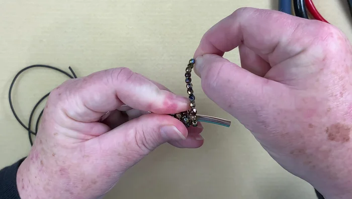 Repeat wrapping: Continue wrapping the wire around the tube, pushing down beads as you go until all beads are on the wire.