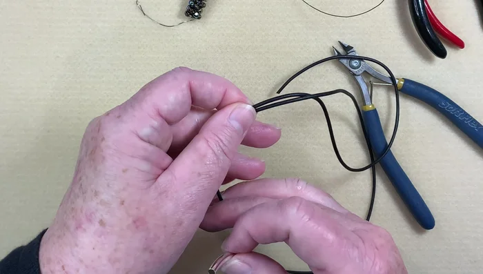 Create barrel knots: Make a barrel knot on each end of the leather cord by wrapping the cord around the tube three times and threading the end through the back of the tube.