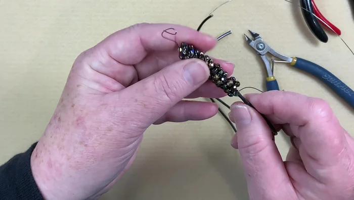 Attach the beaded wire to the leather: Thread both ends of the leather cord through the beaded wire, leaving one end slightly longer.