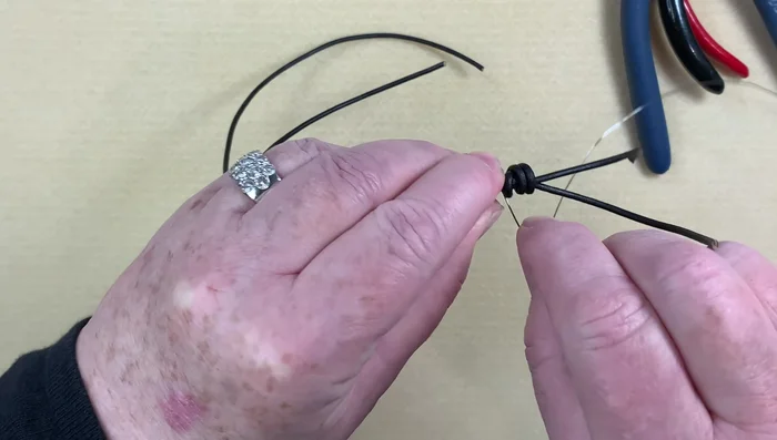 Tighten the barrel knots: Push and pull the leather and beads to snugly tighten the barrel knots, covering any exposed wire.