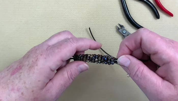Tighten the barrel knots: Push and pull the leather and beads to snugly tighten the barrel knots, covering any exposed wire.