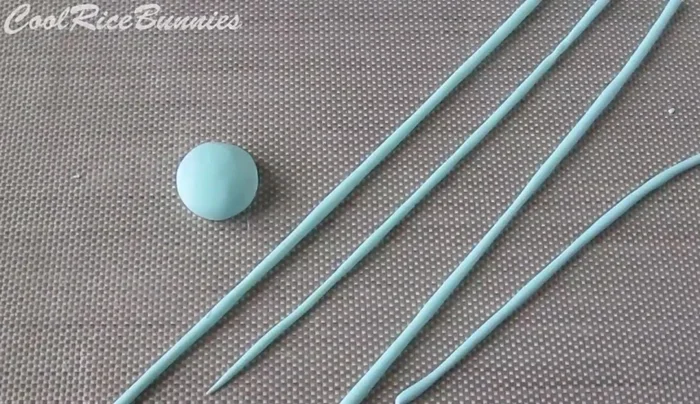 Create yarn balls: Make two dome shapes of your chosen color. Roll out thin coils of the same clay and layer them onto the domes to create a stringy pattern. Attach a small coil to the back, blending it in with a tool or fingers. Optionally, insert head pins to mimic knitting needles.