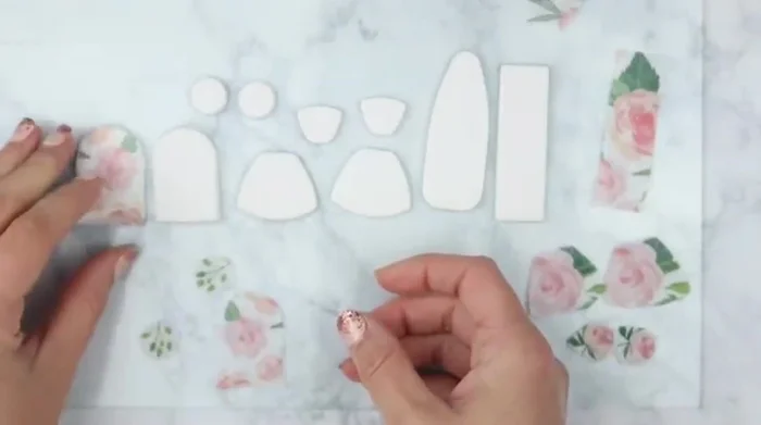 Place the printed side of the napkin pieces down onto the clay, then gently rub them onto the surface using a piece of parchment paper. Avoid pressing too hard to prevent misshaping.