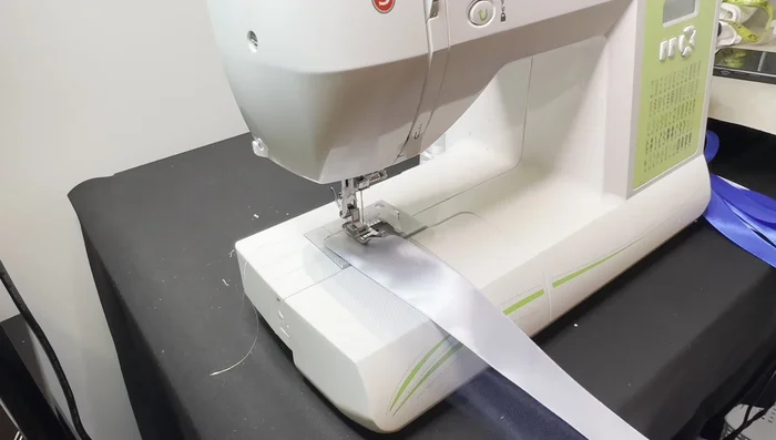 Sew the first layer: Fold the tool in half. Layer the first ribbon onto the tool, leaving space at the top for the elastic channel. Sew the ribbon and channel simultaneously.