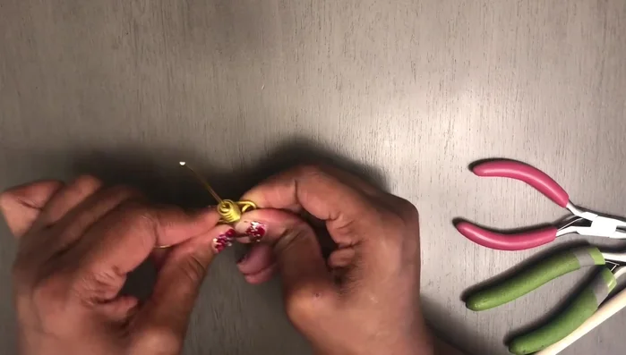 Take the wire to the back of the earring piece. Bring the wire through the front, then back through the other side, repeating this process several times to secure.