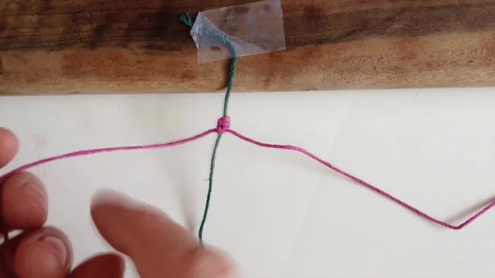 Poke the strand that went under back over to the other side to form a square knot. Pull it tight.