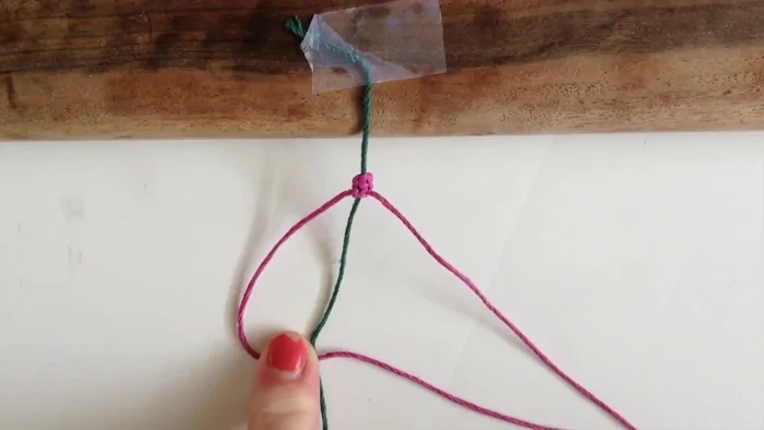 Poke the strand that went under back over to the other side to form a square knot. Pull it tight.