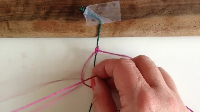 Poke the strand that went under back over to the other side to form a square knot. Pull it tight.