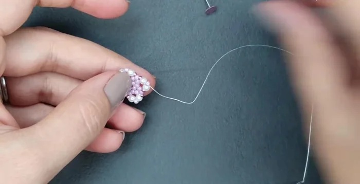 Attach the pin: Pass the thread through a size 11 bead, add another size 11, and pass through the next size 11 from the base. Repeat around, then add and secure the pin. Reinforce the connection with the pin.