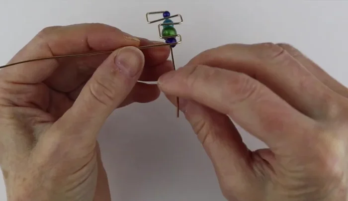 Secure beads: Position the beads and carefully bend the wire to secure them in place. Use pliers to help guide the wire and prevent slipping.