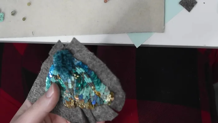 Add a final felt backing, cutting slits for pin, and securing edges with blanket stitch.