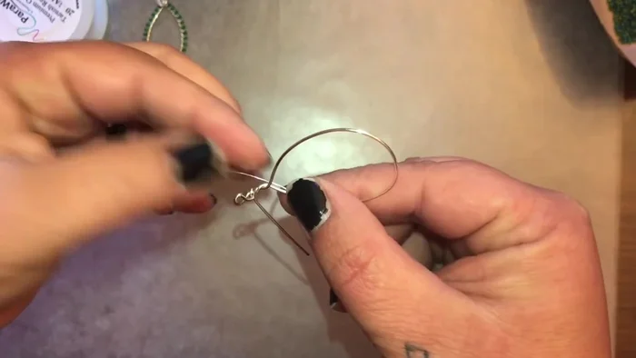 Position the 26 gauge wire behind the teardrop, close to the twist. Thread the wire through the loop twice, leaving a small tail.