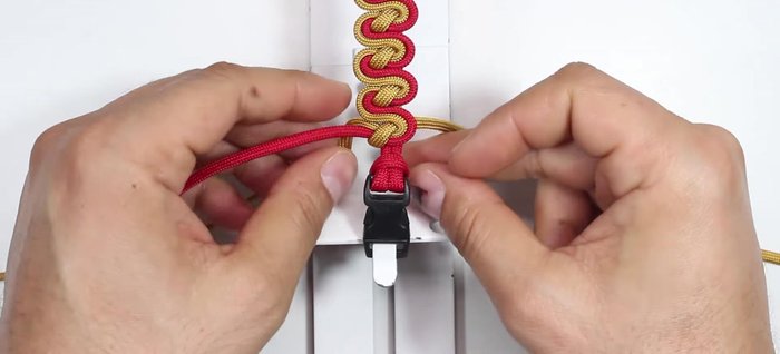 Finish the bracelet: Pass the left gold cord under the bracelet core strands. Pass the red cord on top of the bracelet core strands. Pass the right gold cord under the working ends and over the bracelet core strands, through the loop on the left side. Tie it up to lock the gold and red cords, ensuring a firm structure.