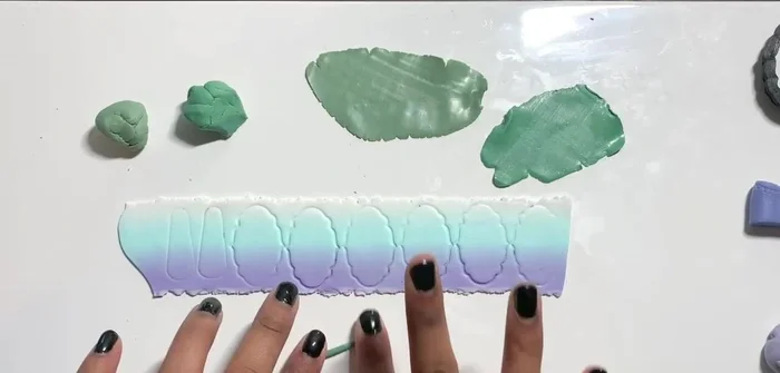 Create stamps using thin green clay snakes on the thinnest pasta machine setting and place three on the base clay.