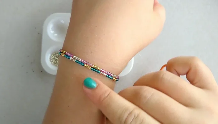 String the beads onto the elastic, following your chosen pattern. Use a needle if necessary, or string directly onto the elastic if it's stiff enough. A time-lapse is shown in the video for this step.