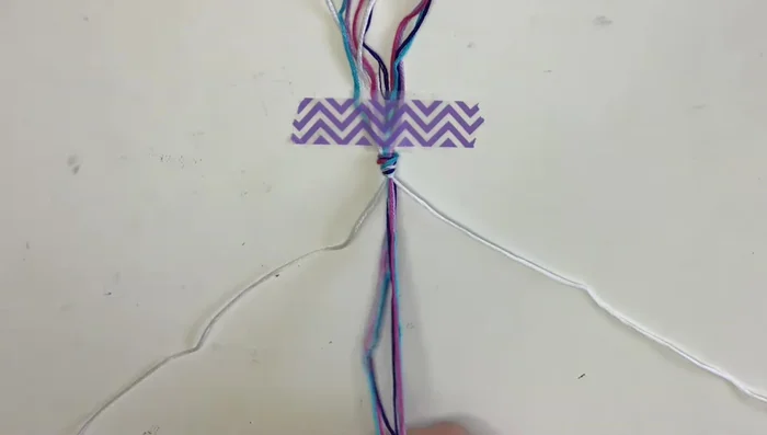 Organize your strings: Arrange the strings so you have one of each color on either side. Use a bracelet book variation (linked in the description) to determine your string order.