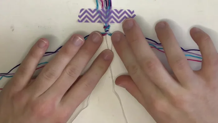 Start with the center: Make one forward knot in the center using the two white strings.