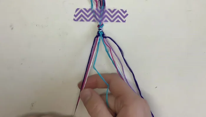 Complete the center rows: Work your way from the center outward using backward knots with the blue strings, then forward knots with the white strings, followed by the pink strings.
