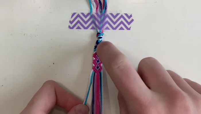 Final center section and finishing: Complete the final center section with white strings. Finish by tying a knot at the bottom and create your desired ties.