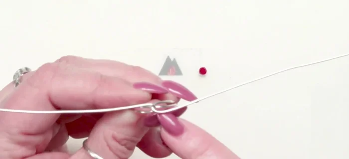 Add the center bead: Wrap the 24 gauge wire around the center wire between the two tails of the 18 gauge wire, securing the bead with 3 tight wraps. Trim and tuck the excess wire.