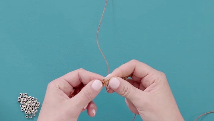 Repeat the knotting process: Continue the braiding pattern, consistently wrapping the top leather strand around your finger and through the loop, placing it to the right of the previous loop, and pulling tight. The pattern should resemble a snake braid or herringbone.