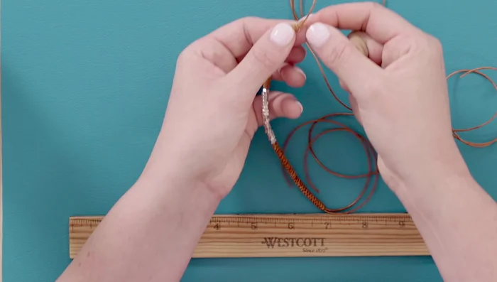 Create the clasp: Cut the tails to about 4 inches. Make a loop with the bracelet, overlapping the ends. Take an extra foot of leather, and wrap it several times (5-6) around the overlapping tails, then pass the end through the loop. Pull tight and trim the excess.