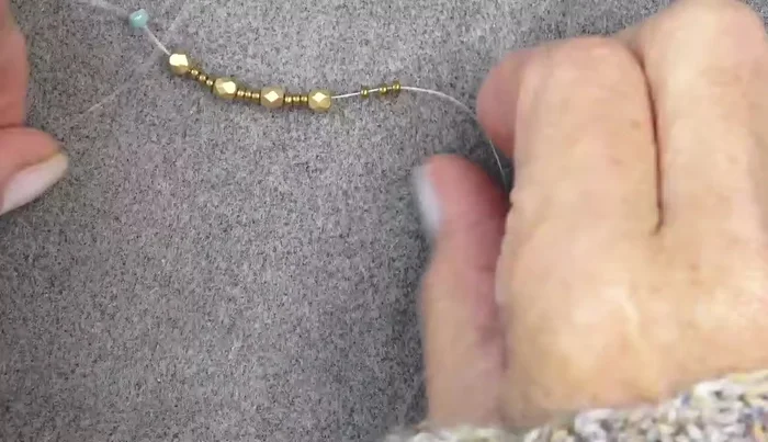 Add another round of beads: 11/0, Delica, 11/0 around each fire polish bead, pushing them in front of the fire polish beads.