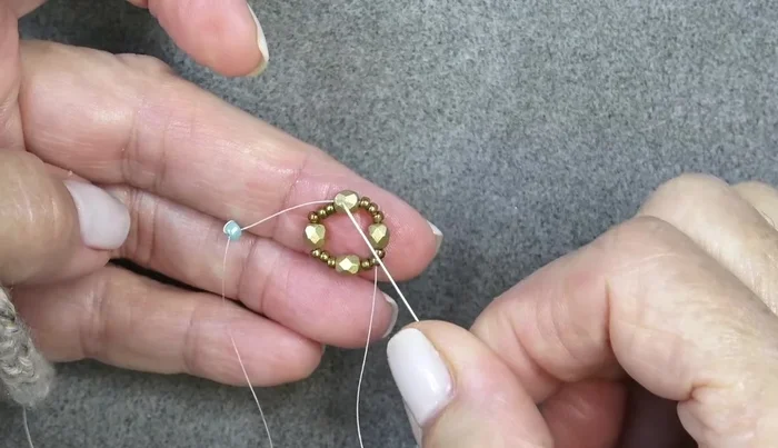 Add another round of beads: 11/0, Delica, 11/0 around each fire polish bead, pushing them in front of the fire polish beads.